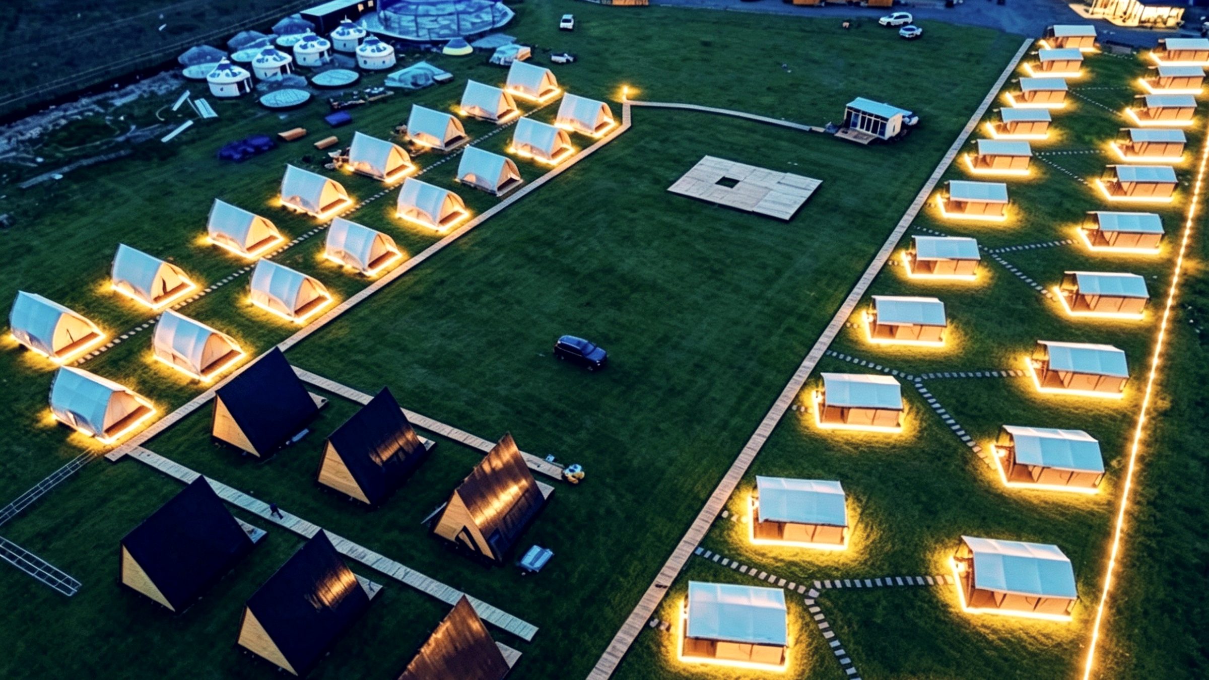 Lit modular cabins on a resort site at dusk